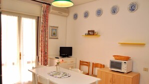 Une pièce comprenant une table à manger, des chaises, un téléviseur, un four à micro-ondes et un meuble.