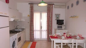 Une cuisine compacte équipée d’un lave-linge, d’une table à manger avec des chaises et d’un four à micro-ondes.