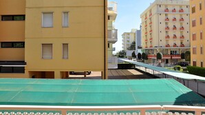Un immeuble résidentiel à plusieurs étages, doté de balcons, d’une galerie couverte et d’une marquise verte.