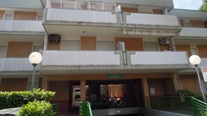 A multi-story residential building with balconies, a green sign indicating 'Residence Albatros,' and a bicycle parking area. - Holiday apartment mit Terrasse (Bibione)