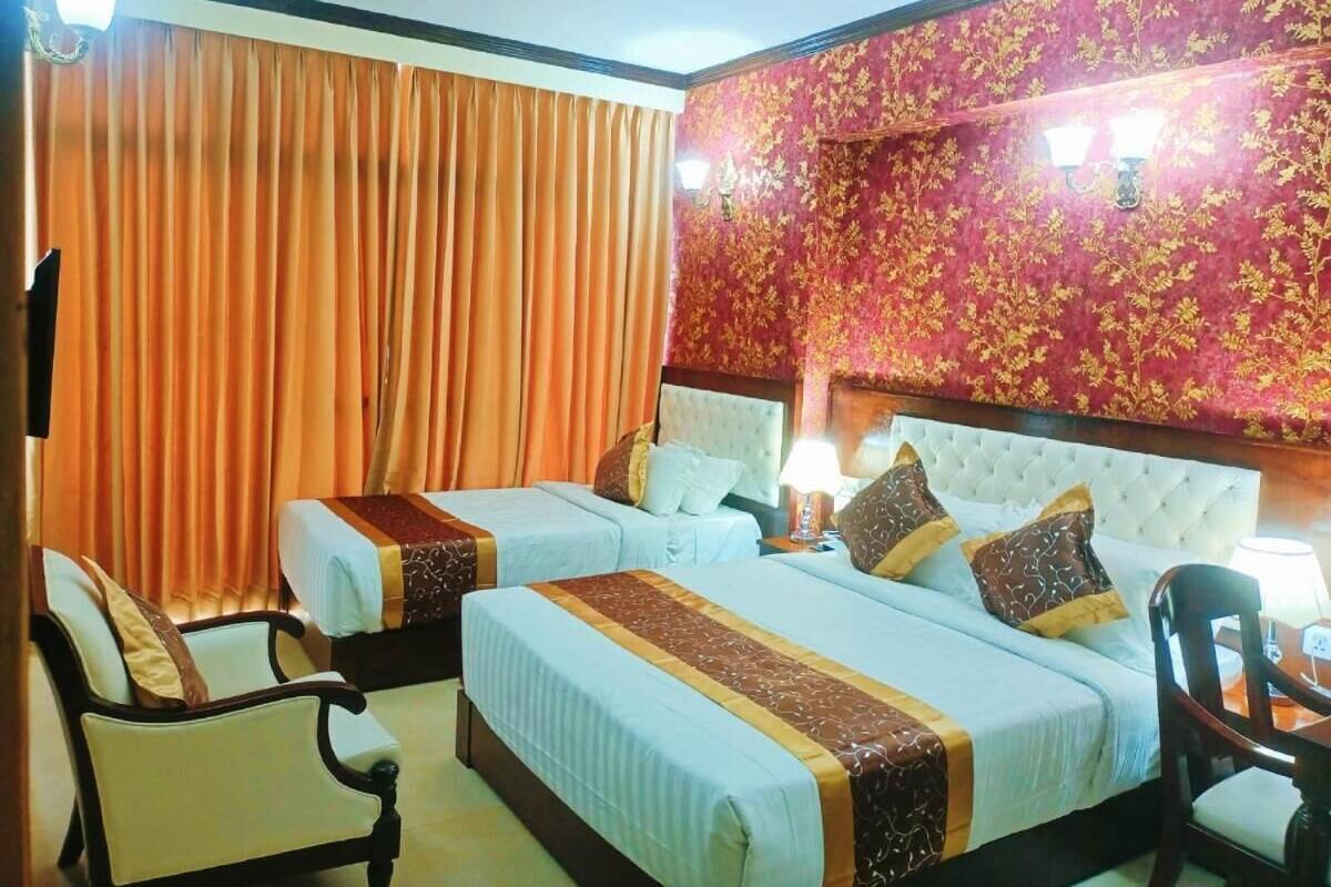 A hotel room with two beds, a chair, and a table.