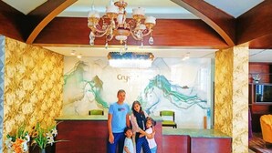 A reception area with a wooden reception desk, a chandelier, and a mural on the wall. - Hotel Crystal Rose sylhet (Sylhet)
