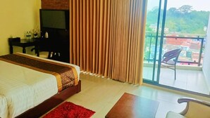 A hotel room with a bed, a desk, a chair, a TV, and a balcony with a view of the city. - Hotel Crystal Rose sylhet (Sylhet)