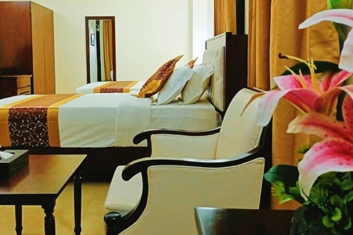 A hotel room with a bed, a sofa, a table, and a TV.