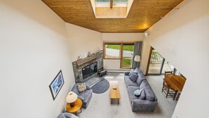 A spacious living room with a fireplace, a sofa set, a coffee table, and a dining area.