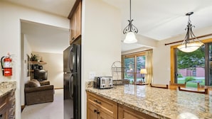Eine moderne Küche mit Granit Arbeitsplatten, einem integrierten Kühlschrank und Pendelleuchten.