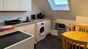 A compact kitchen with a washing machine, a small sink, a toaster, and a skylight.