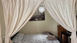 Une chambre à coucher avec un lit, une commode en bois et un luminaire suspendu.