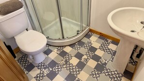 Une salle de bain avec une douche à parois de verre, des toilettes et un lavabo.