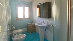 Un baño con inodoro, bidé, lavamanos y ducha.