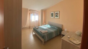 Un dormitorio con cama, mesita de noche y ventana con cortinas.