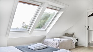 A bedroom with two beds, a skylight, and a view of trees. - Staysville - Eiganes (Stavanger)