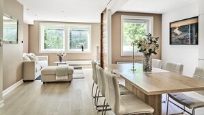 A modern dining area with a wooden table, cushioned chairs, and a vase of flowers. - Staysville - Eiganes (Stavanger)