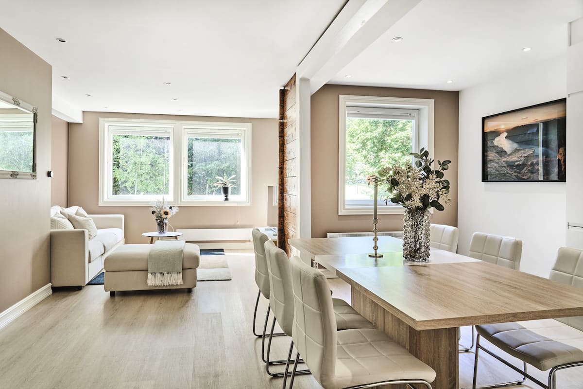 Un espace repas moderne avec une table en bois, des chaises rembourrées et un vase de fleurs.