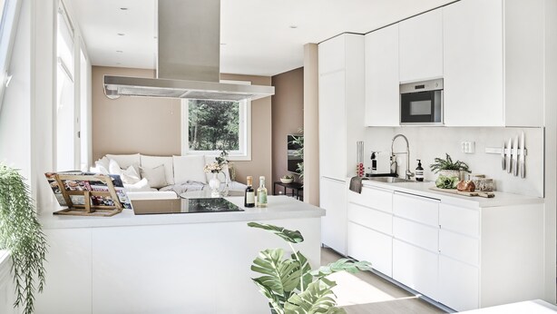 A modern kitchen with white cabinetry, a central island, and a large window providing natural light. - Staysville - Eiganes (Stavanger)