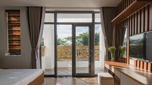 Un dormitorio moderno con una cama grande, puertas de cristal correderas a un balcón y un televisor en la pared.