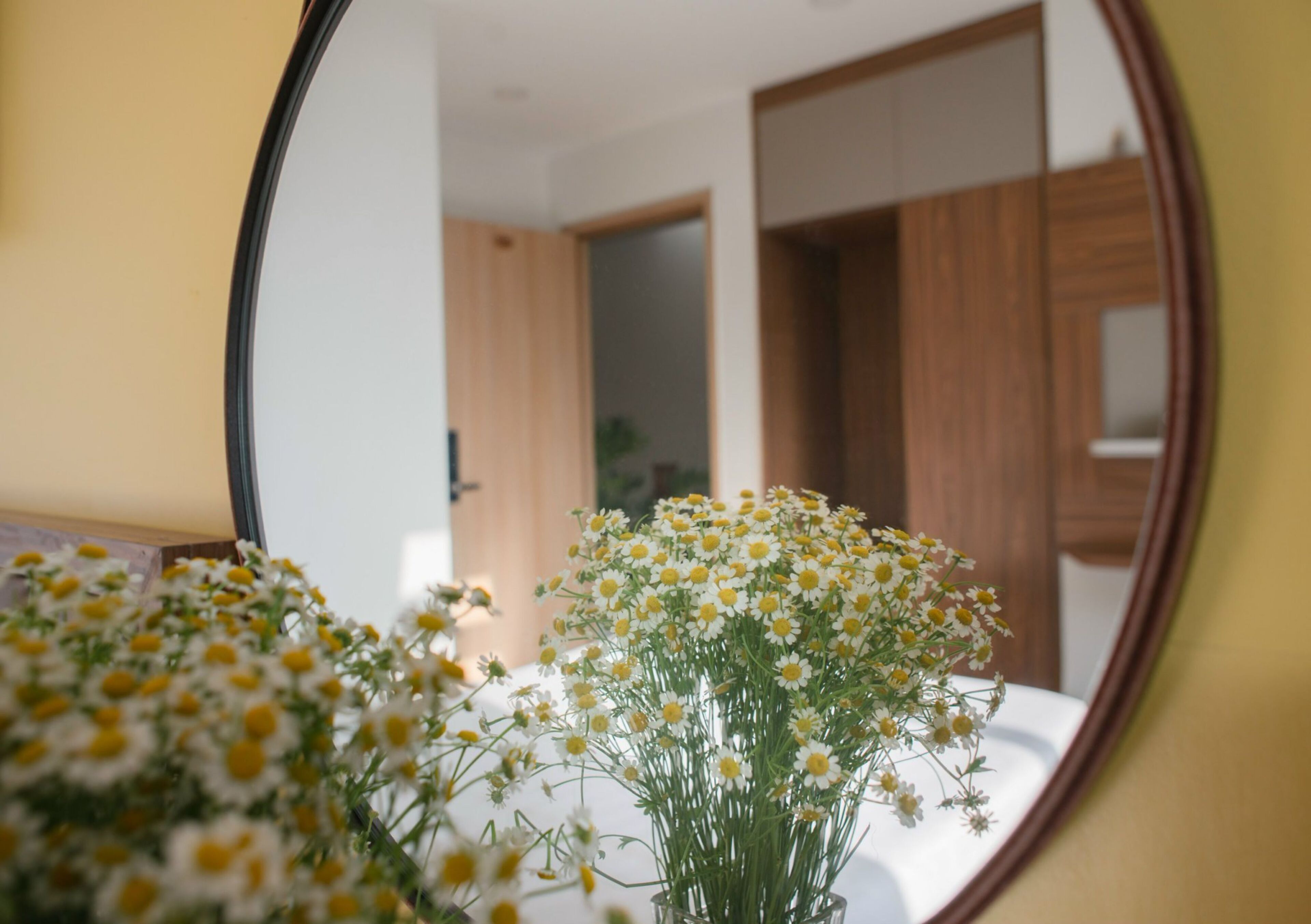 A mirror reflecting a room with a wooden door and a white wall.