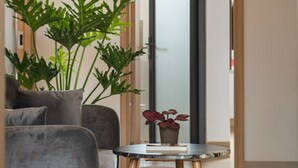 Una sala de estar moderna con un sofá gris, una mesita redonda y una planta en maceta.
