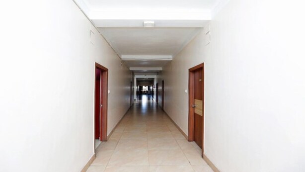 A long, narrow hallway with white walls and a tiled floor, leading to a door at the end. - MeroStay 210 Hotel Tone (Kathmandu)