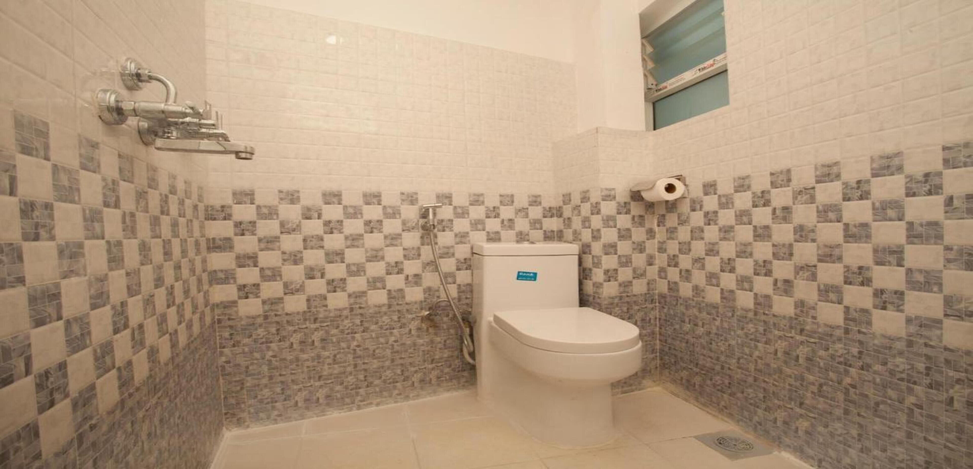 A small bathroom with a toilet, a shower, and tiled walls.