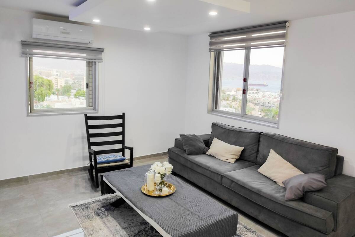Un salón moderno con un sofá gris, una butaca negra y una mesa de centro con objetos decorativos.