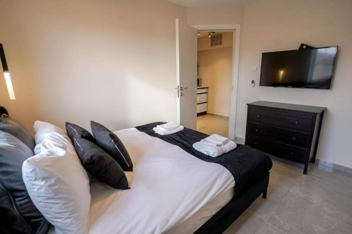 Una habitación de hotel con una cama, un televisor montado en la pared y un aparador.