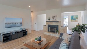 A modern living room with a flat-screen TV, a fireplace, a sofa, and a coffee table. - 3896 Gather and Rest - Mountain Views, Large Patio (Del Rey Oaks)