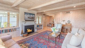 A spacious living room with a fireplace, a piano, and a large rug.