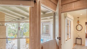 A wooden door leading to a covered patio area with a view of a garden.