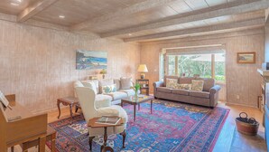 A spacious living room with a grand piano, two sofas, a coffee table, and a colorful rug.