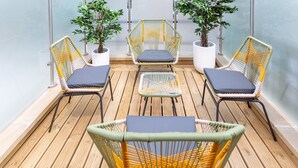 A balcony with wicker chairs and a small table, surrounded by potted plants. - 3 Bedroom flat with Terrace in Central London (London)