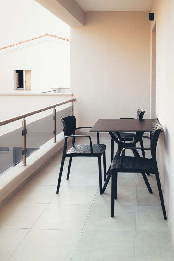 A balcony with a table and chairs, a railing, and a view of a building.