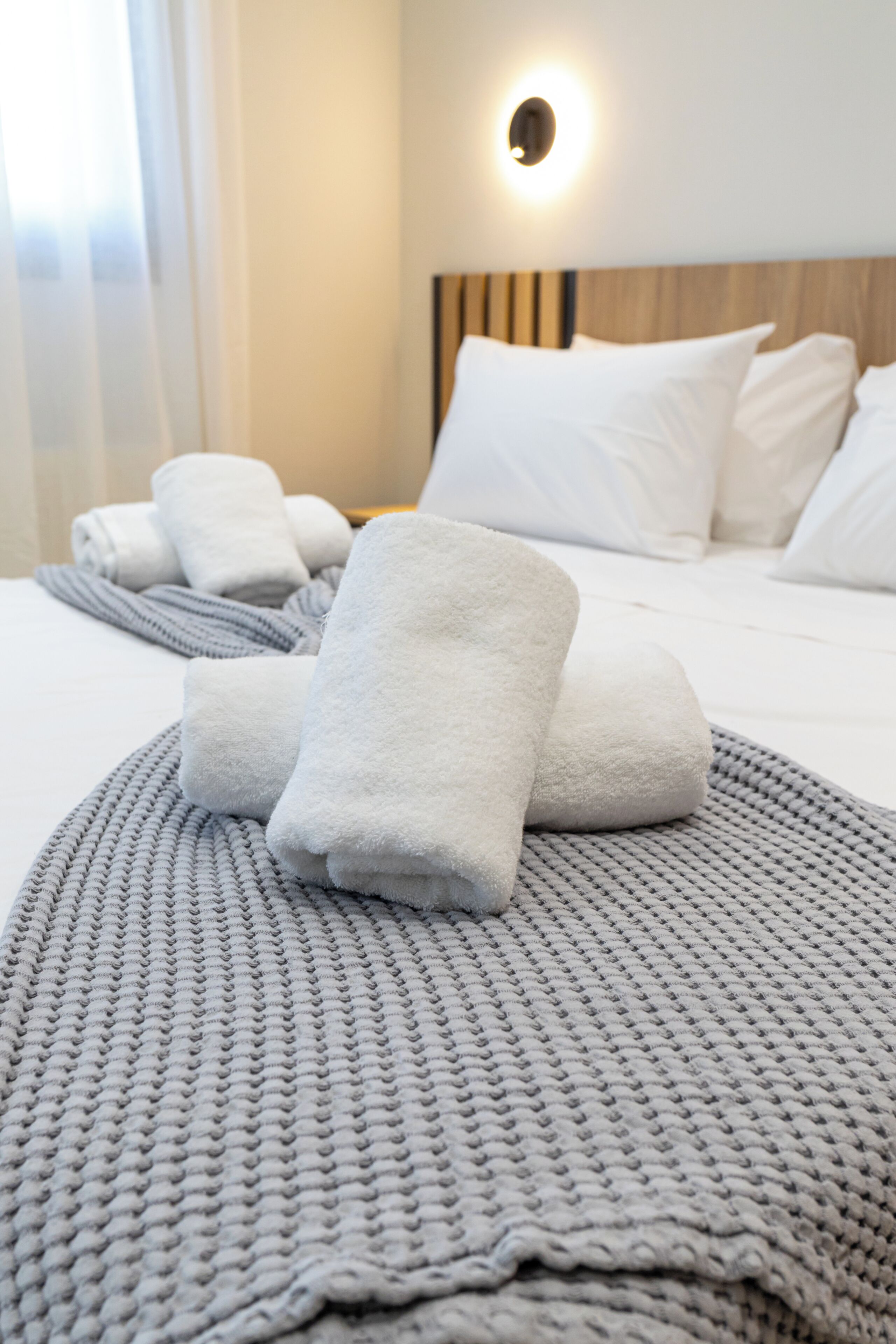 A neatly made bed with white linens and a gray knitted blanket.