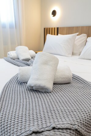A neatly made bed with white linens and a gray knitted blanket.