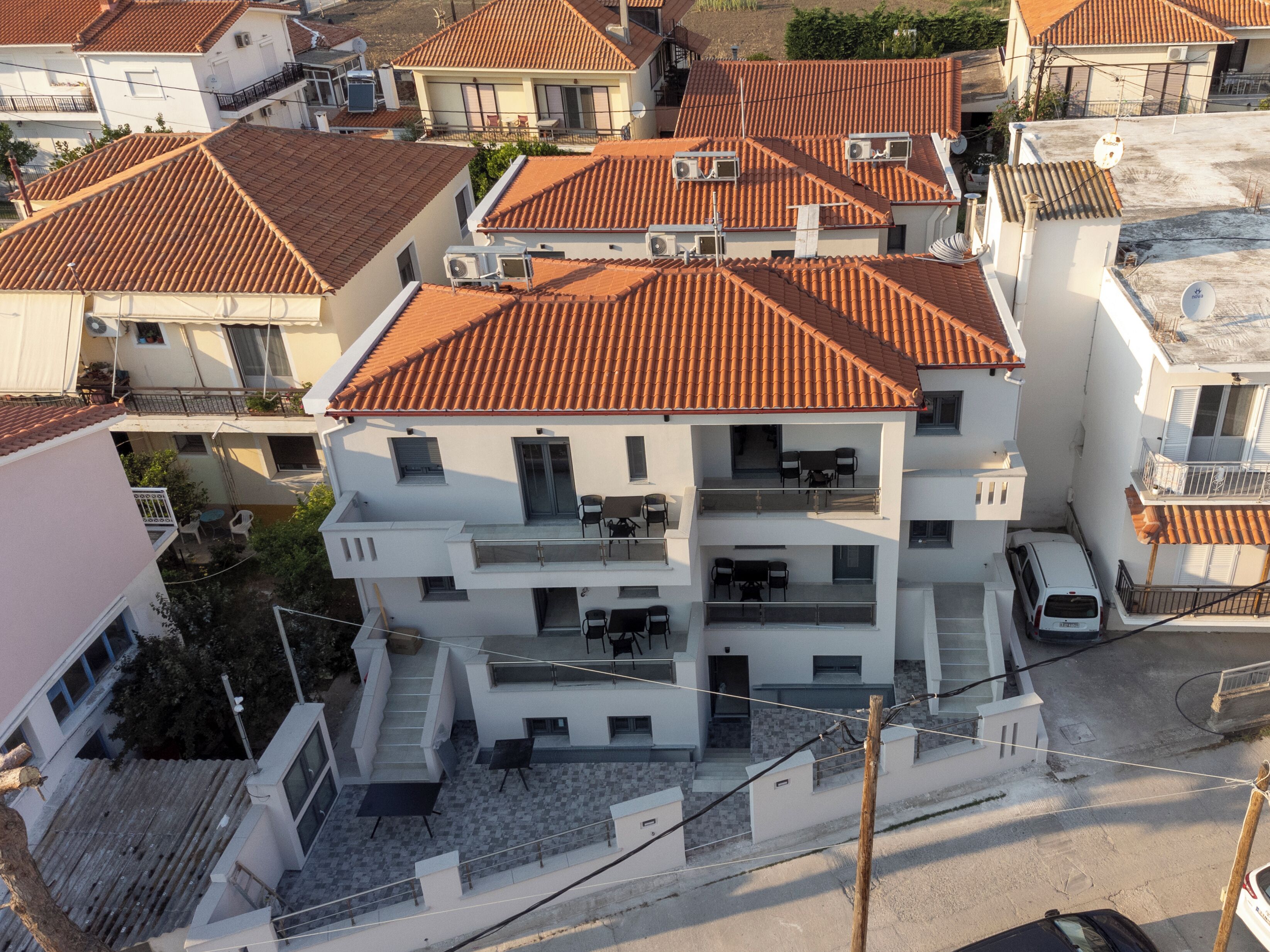 A multi-story residential building with a tiled roof, balconies, and air conditioning units.