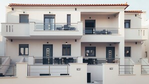 A modern multi-story residential building with balconies, staircases, and a flat roof.