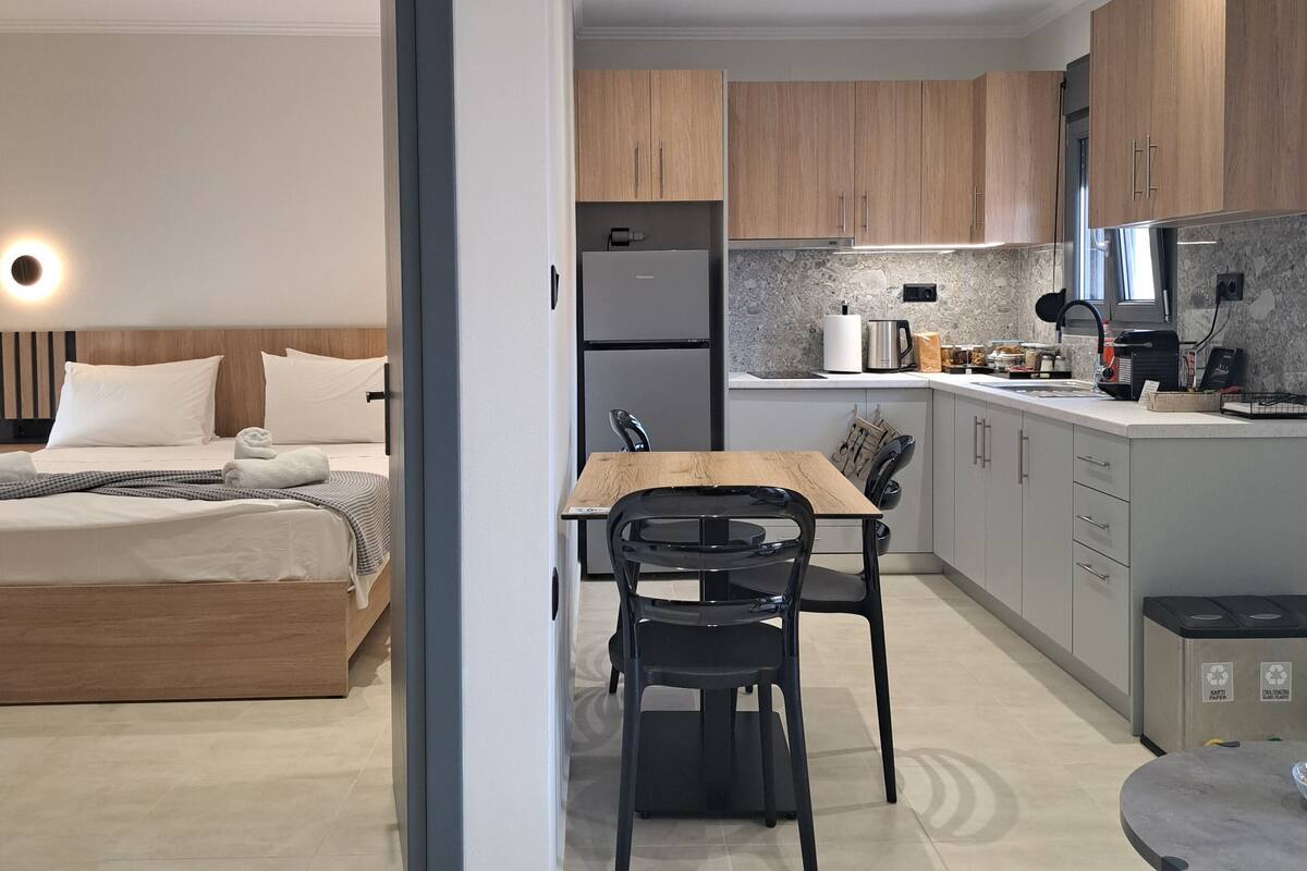 Una habitación de hotel moderna con cama, una mesa de comedor y una zona de cocina.