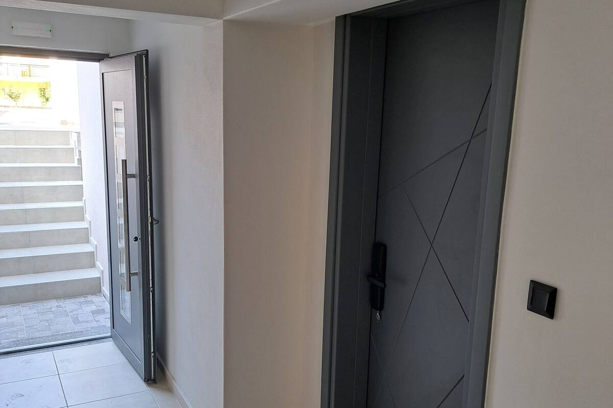 Un pasillo con una puerta oscura y una pared de color claro.