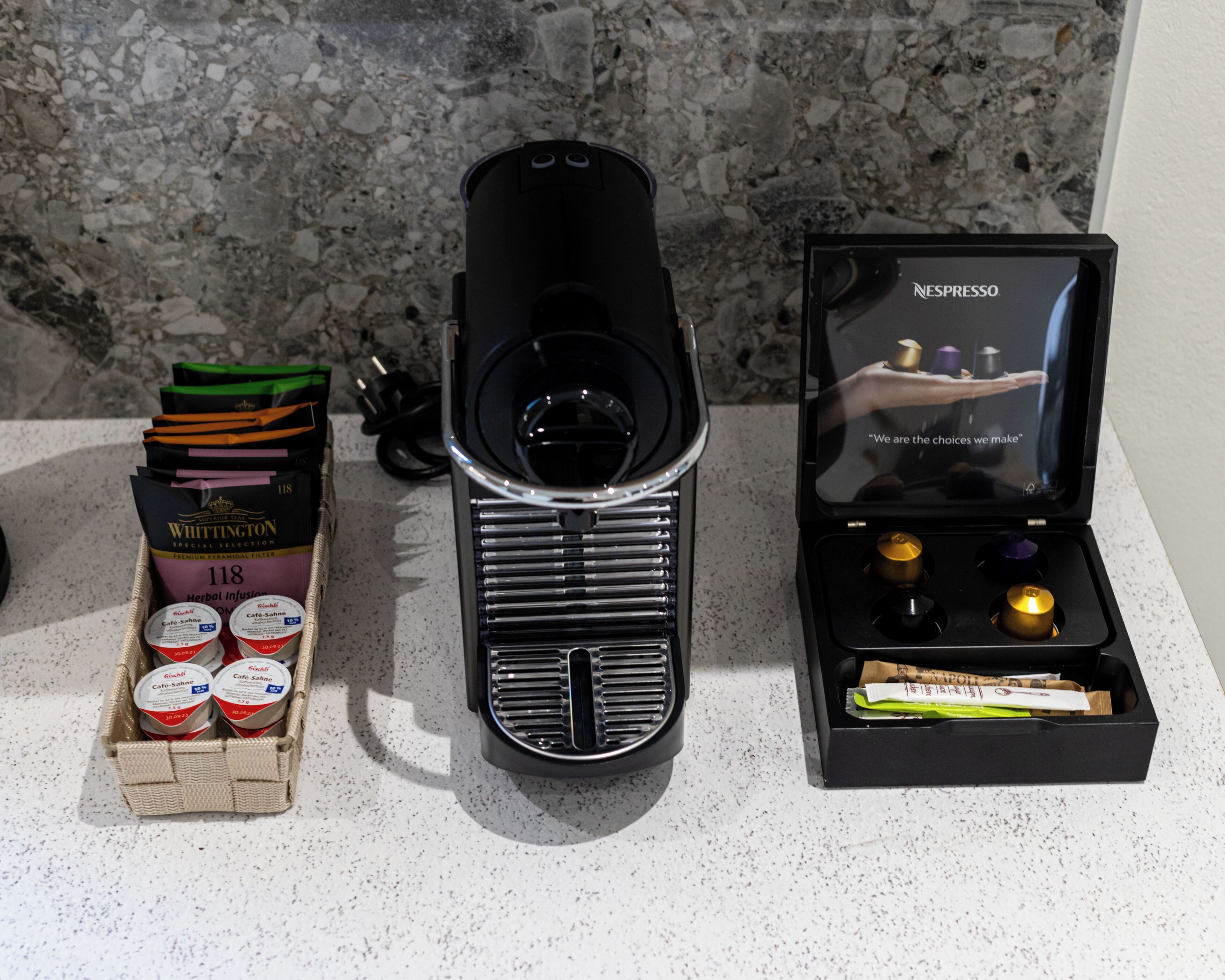 A coffee machine, a box of coffee pods, and a display of coffee capsules.
