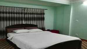 A single bed with white bedding in a room with green walls and a checkered floor. - MeroStay 251 Hotel Air (Kathmandu)