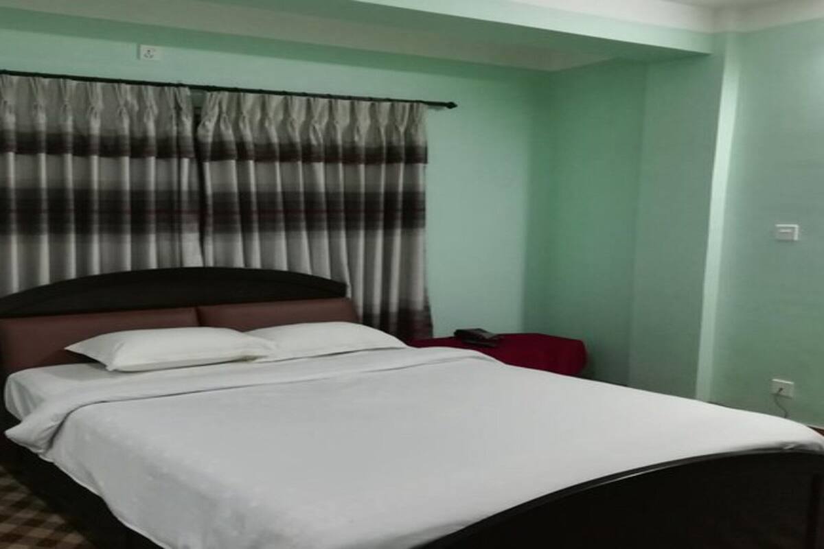 Een enkel bed met witte lakens in een kamer met groene wanden en een geruite vloer.