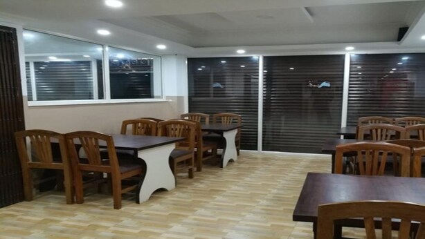 A dining area with wooden tables and chairs, large windows, and a tiled floor. - MeroStay 251 Hotel Air (Kathmandu)