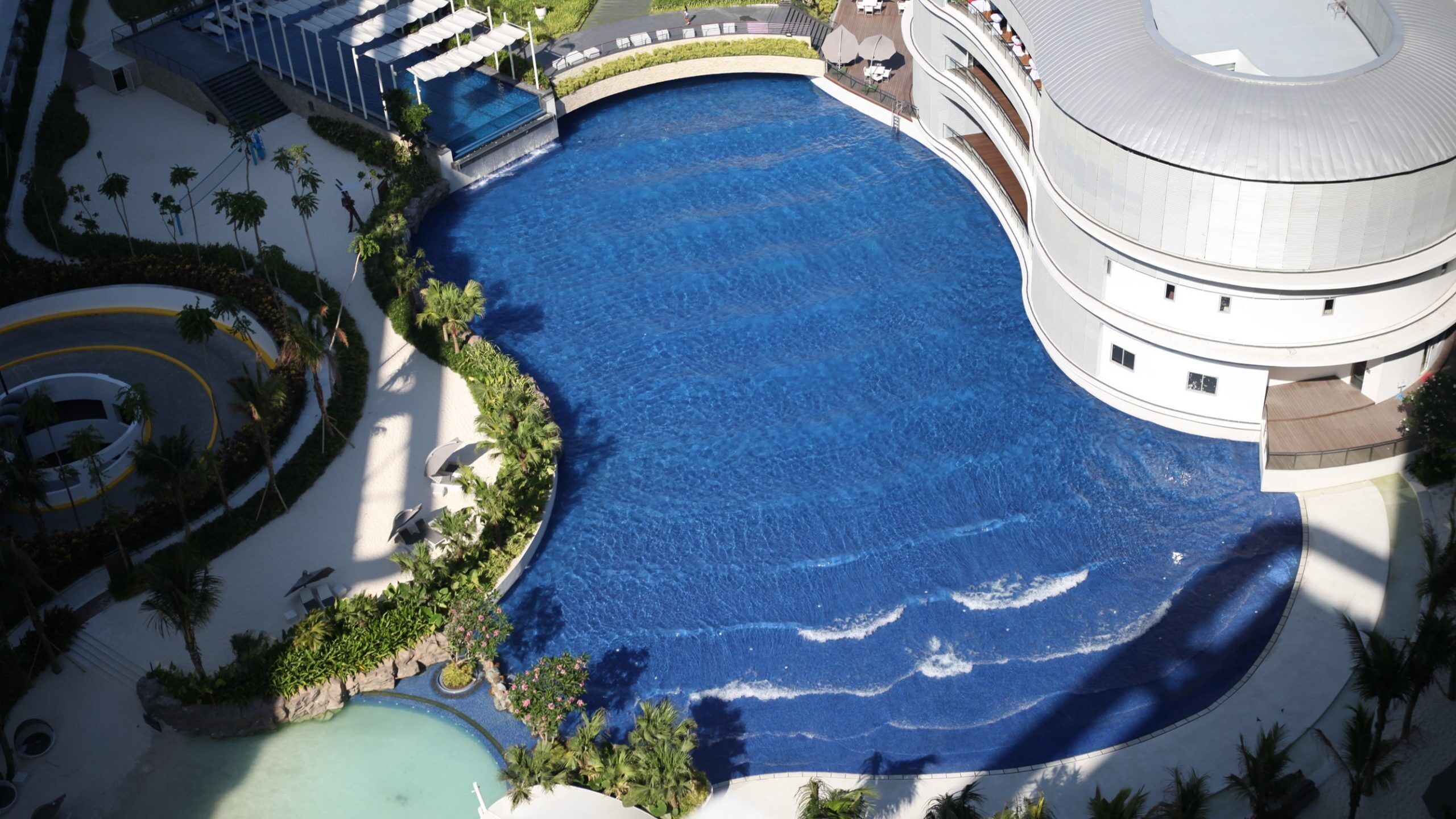 A large, curved swimming pool with a circular building adjacent to it.