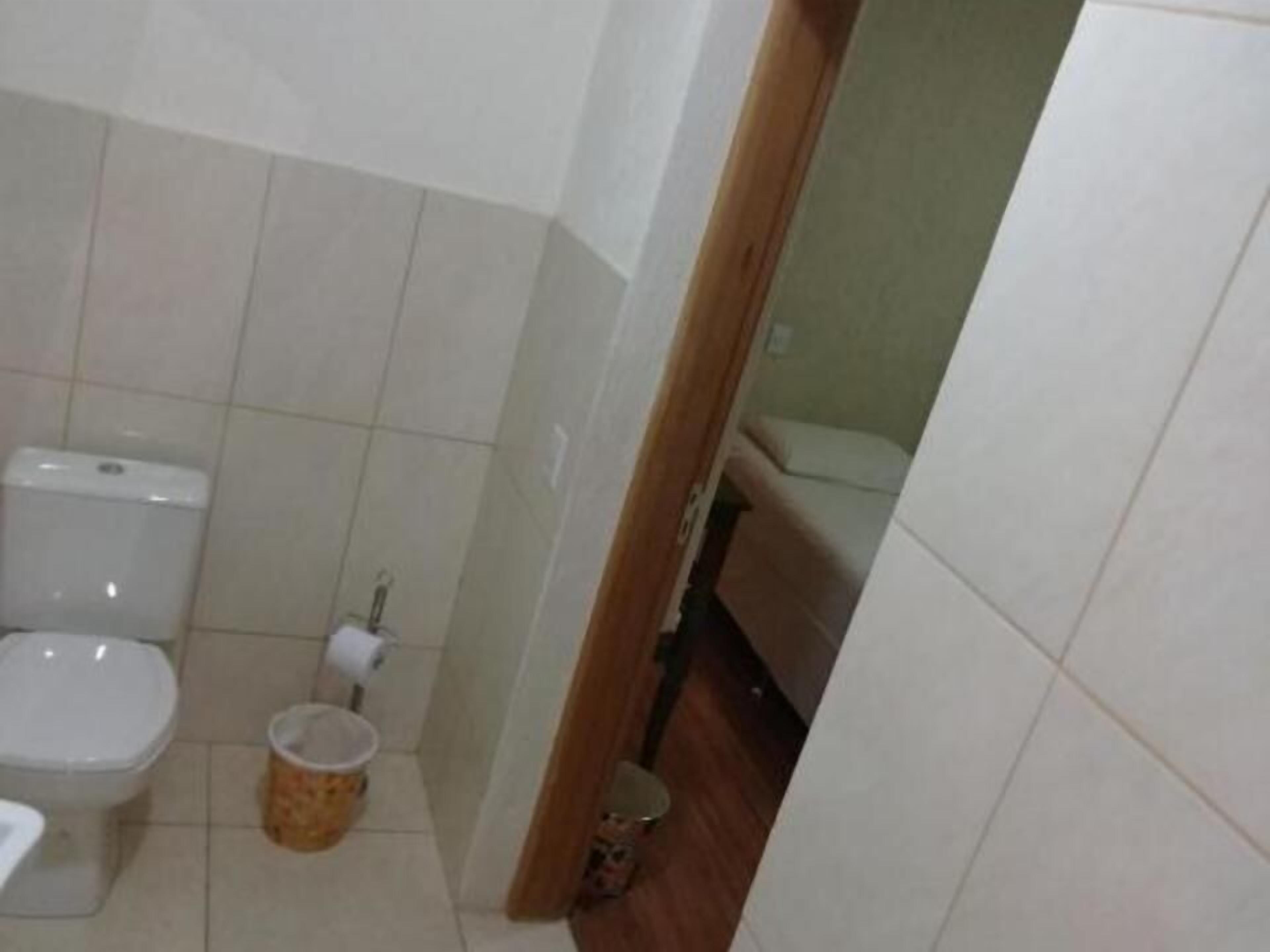 Um banheiro pequeno com vaso sanitário, lixeira e porta-papel higiênico.