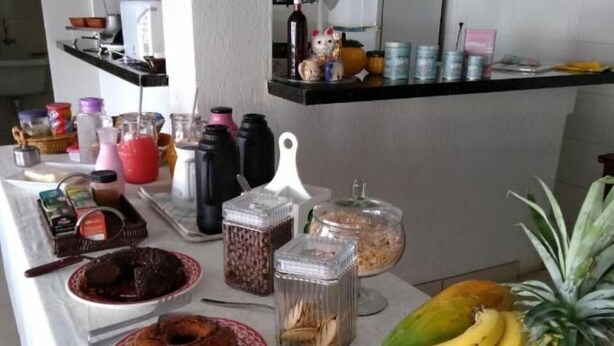 A buffet table with various food items including a bundt cake, bananas, and a pineapple. - Ipê Rosa Hotel (Bauru)