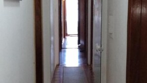 A narrow hallway with wooden doors on either side and a tiled floor. - Ipê Rosa Hotel (Bauru)