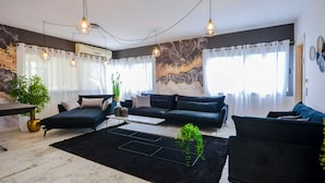 Ett modernt vardagsrum med en svart soffgrupp, ett soffbord och en svart matta. Tre hänglampor är upphängda från taket.