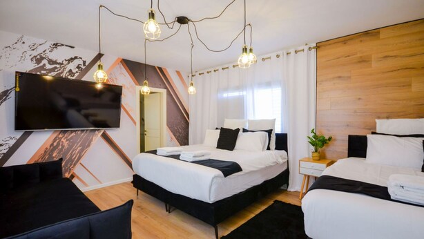 Ett modernt hotellrum med en stor säng, en mindre säng, en TV och ett skrivbord.