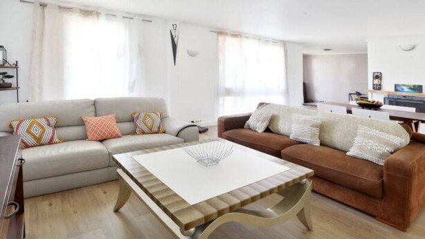 Ein modernes Wohnzimmer mit einem beigefarbenen Sofa, einem braunen Sofa und einem Couchtisch aus Holz.