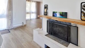 Ein modernes Wohnzimmer mit Kamin, Holzboden und weißem Heizkörper.